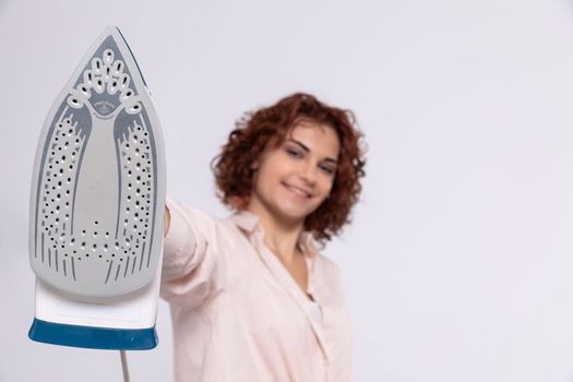 The foot of a household iron. Close-up view. A girl prepared to do housework. Readiness to iron. A hand drawn up over itself.
