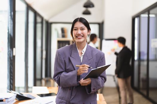 Portrait of young attractive asian female office worker in formal business suits smiling at camera in office