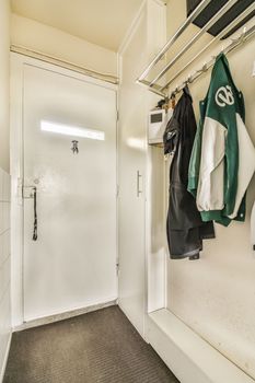 the inside of a room with clothes hanging on hooks and coat racks attached to the wall in front of the door