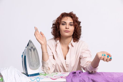 Sitting position on a chair. The girl rests her hands on the ironing board. A young girl will iron men's shirts.