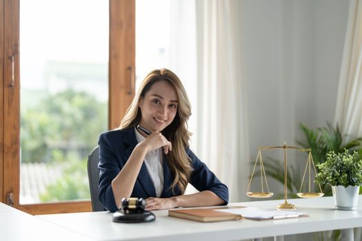 Business woman and lawyers discussing contract papers with brass scale on wooden desk in office. Law, legal services, advice, Justice and real estate concept