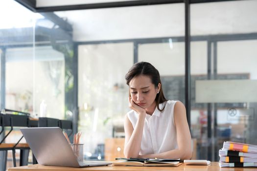 Young Business Asian women are stressed while working on laptop, Tired asian businesswoman with headache at office, feeling sick at work copy space in workplace an home office..