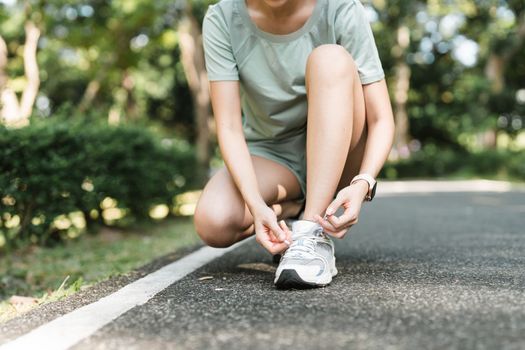 Woman tying shoe laces. Closeup of female sport fitness runner getting ready for jogging outdoors