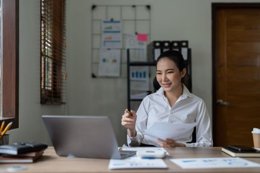 Woman accountant using calculator and laptop computer in office, finance and accounting concept.