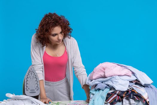 Not too thrilled, the housewife, that so many shirts to iron. Ironing board with crumpled shirts and iron ready to go.