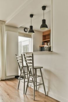 Table with chairs and flowers located near lounge area and kitchen in spacious room of contemporary apartment