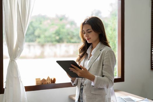 Woman accountant using calculator and digital tablet computer in office, finance and accounting concept