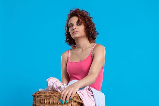 A very tired woman , carries a heavy wicker basket with washed clothes. Overworked woman with dark and curly hair. Monotonous housework.