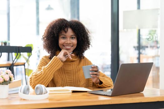 Photo of cheerful joyful mixed race woman in yellow shirt smiling work on laptop talk speak video call online. Smart ethnic female in earphones study distant on computer at home. Education concept...