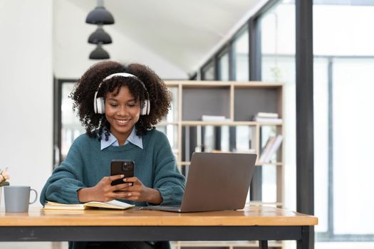 Photo of cheerful joyful woman playing games and wearing wireless headphones at home Play game on your smartphone that wins the moment of victory. Fun and enjoyable vacation.