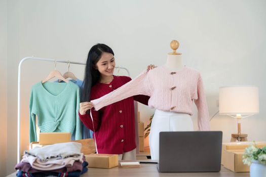 Portrait of Starting small businesses SME owners, Asian woman check online orders Selling products working with boxs freelance work at home office, sme business online small medium enterprise..
