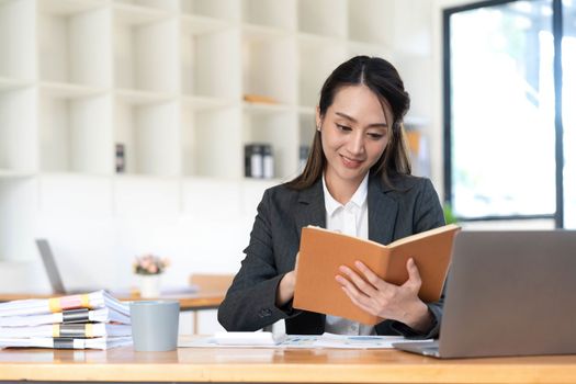 Asian businesswoman meeting at the office, taking notes and using a tablet at the office..