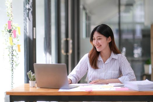 Young Asian businesswoman is happy to work at the modern office using a tablet..