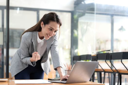 Excited happy Asian woman looking at the phone screen, celebrating an online win, overjoyed young asian female screaming with joy, isolated over a white blur background.