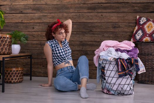Short curly dark-colored hair. The surprised girl sees on the floor and is surprised by the large amount of wet laundry to be hung up.