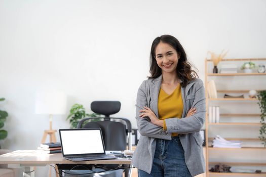 Smiling Asian beautiful female professional manager standing with arms crossed looking at camera