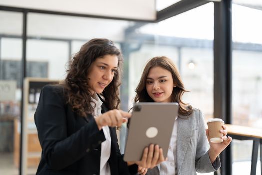 Diverse businesspeople cooperate work together discussing company financial statistics, multiracial colleagues collaborate brainstorm with finance on tablet