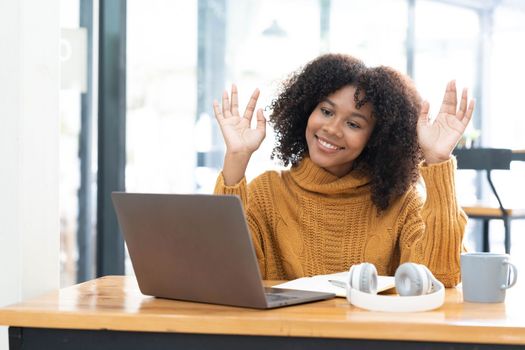 Photo of cheerful joyful mixed race woman in yellow shirt smiling work on laptop talk speak video call online. Smart ethnic female in earphones study distant on computer at home. Education concept...