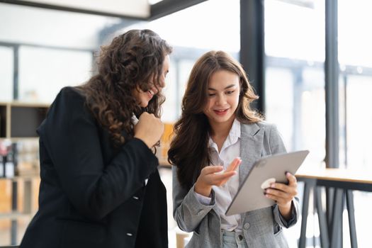 Diverse businesspeople cooperate work together discussing company financial statistics, multiracial colleagues collaborate brainstorm with finance on tablet