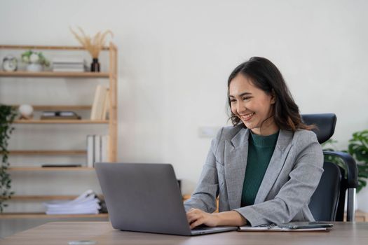 Asian Business woman using calculator and laptop for doing math finance on an office desk, tax, report, accounting, statistics, and analytical research concept..