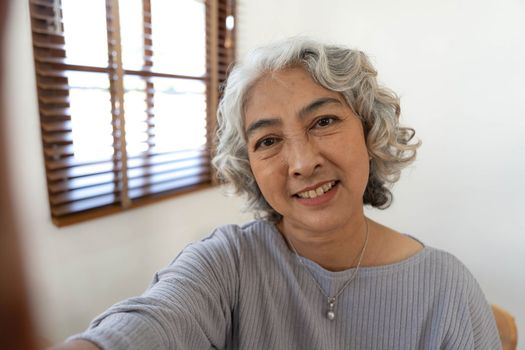 Happy Asian Elderly taking selfie photos with smartphone together in house. Portrait Senior people smiling and looking at camera