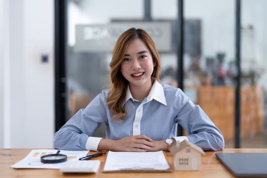 Young asian businesswoman real estate agent looking on camera at her office