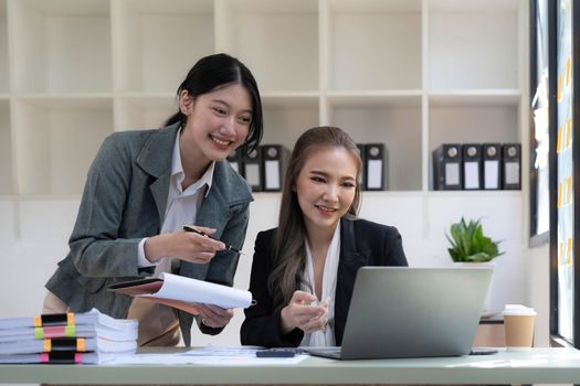 Two young Asian business woman talk, consult, discuss working with new startup project idea presentation analyze plan marketing and investment in the office...