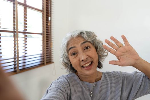 Happy Asian Elderly taking selfie photos with smartphone together in house. Portrait Senior people smiling and looking at camera