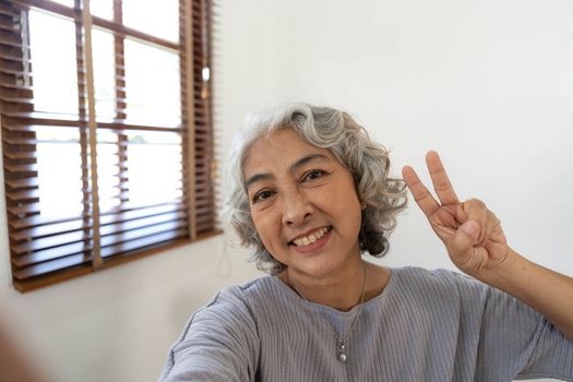 Happy Asian Elderly taking selfie photos with smartphone together in house. Portrait Senior people smiling and looking at camera