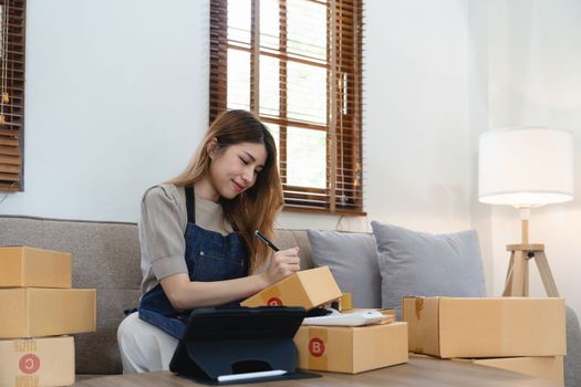 Asian woman freelancer sme business online shopping working with parcel box at home - SME business online and delivery concept.