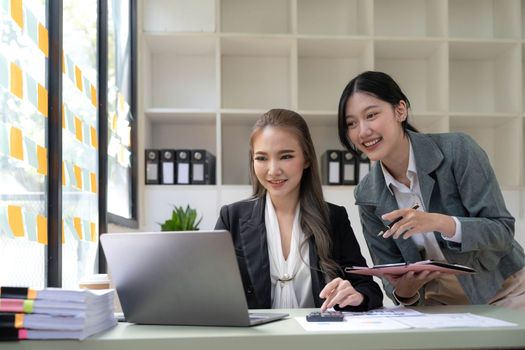 Two young Asian business woman talk, consult, discuss working with new startup project idea presentation analyze plan marketing and investment in the office...