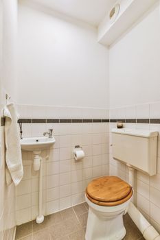 Interior of narrow restroom with sink and wall hung toilet with white walls and checkered floor