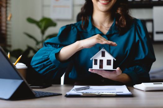 Businesswoman use their hands to protect the red roofs, the concept of protecting houses using the gestures and symbols of real estate investors, taking care of credit and contracts