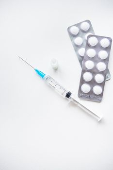 Preparation for vaccination against covid-19. Syringe, vaccine, pills, medical mask on a white table