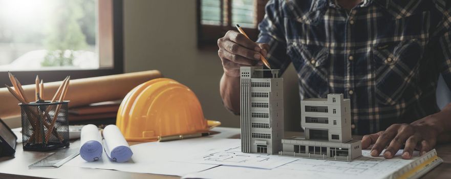 Image of engineer drawing a blue print design building or house, An engineer workplace with blueprints, pencil, protractor and safety helmet, Industry concept.