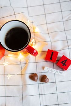 Two cups of coffee in red cups on a background of chocolate canfet in the form of a heart. Morning surprise for Valentine's Day. View from above