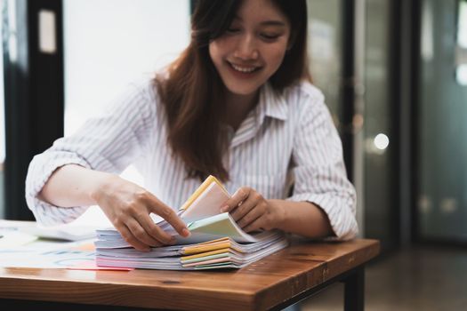 Employee woman hands working in stacks paper files for searching and checking unfinished document achieves on folders papers. business accounting concept