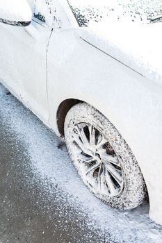 Hand washing with high pressure water in a car wash outside. The car is full of foam. The concept of hand washing, self-service