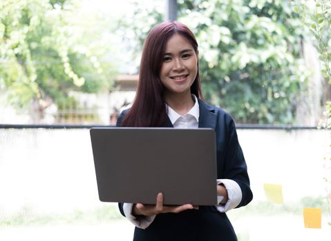Attractive young asian woman using laptop computer while standing in a office...