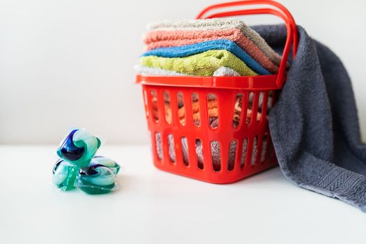 Multi-colored towels lie in a red laundry basket on a white background. Washing and ironing clothes, top view