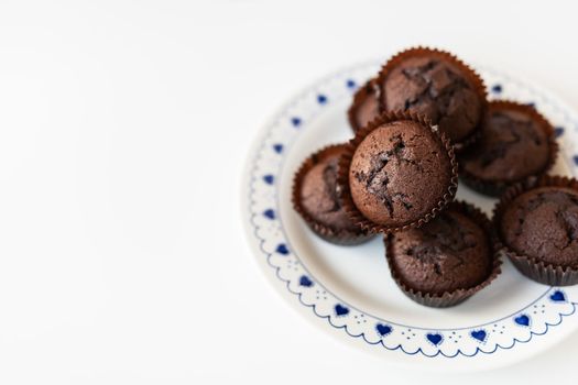 Chocolate muffins lie on a white plate with small hearts. Close-up, space for an inscription