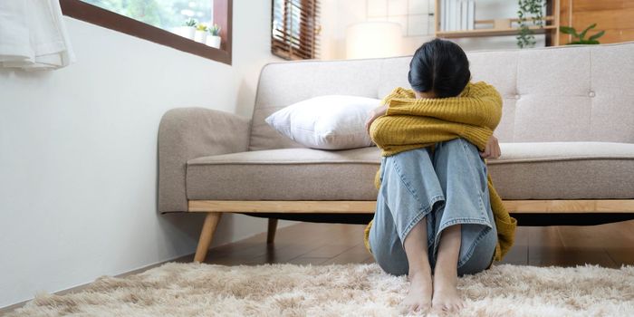 Hand on temples of young unhappy sadness Asian girl sitting on sofa. She is feeling not very good due to her sickness and having a headache. Seen from the front. Stress and sickness concept...