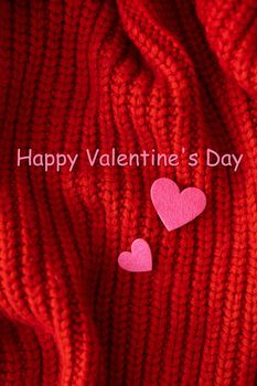 Decorative pink heart on a red knitted background, top view. Lettering Happy Valentine's Day