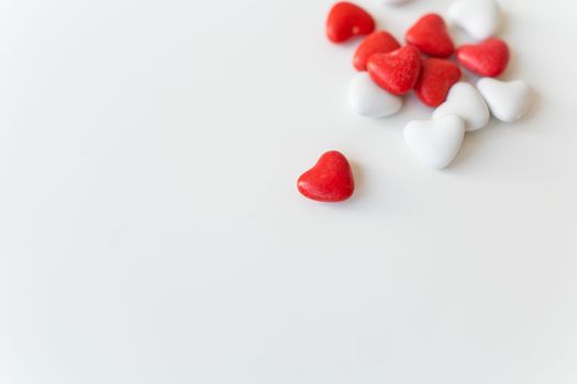 Valentine's day pattern background flat lay top view of red and white heart shaped candies scattered on white background. Place for an inscription