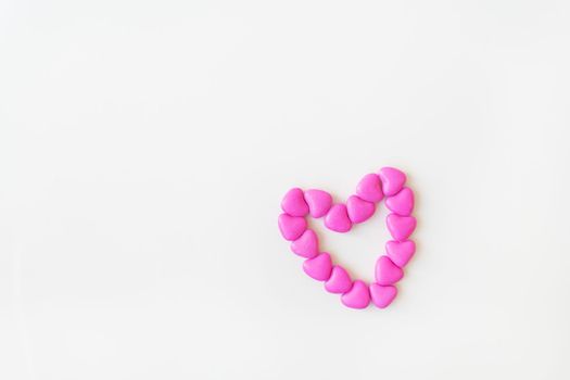 Valentine's day pattern background flat lay top view of heart shaped pink candies scattered on white background. Place for an inscription