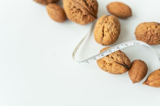 Beautiful whole walnut kernels, whole nuts in shell on a white table. Centimeter among nuts, low calorie nuts. Selective focus