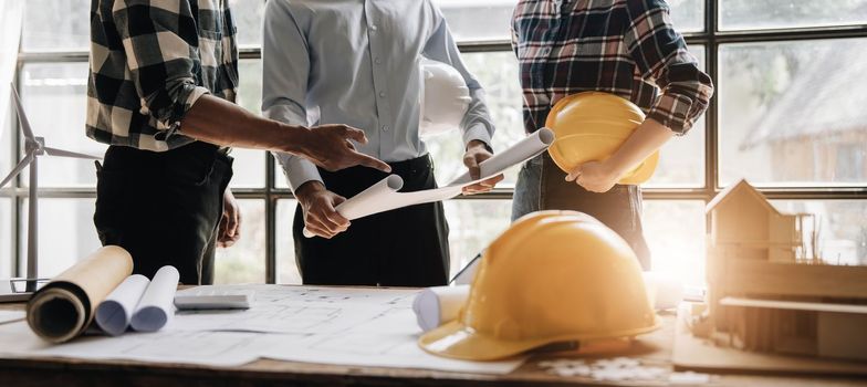 Civil engineer teams meeting working together wear worker helmets hardhat on construction site in modern city. Foreman industry project manager engineer teamwork. Asian industry professional team..
