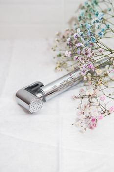 Hygiene and cleanliness concept. New hygienic chrome-plated shower in hand against a background of white tiles. Bathroom