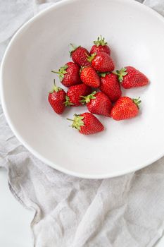 Juicy, tasty, ripe strawberries on a plate, top view. Vertical photo. Place for an inscription