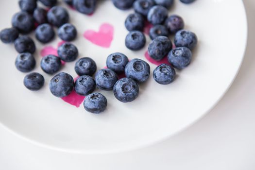 Delicious blueberries lie on a plate with a heart inside. Delicious and healthy food